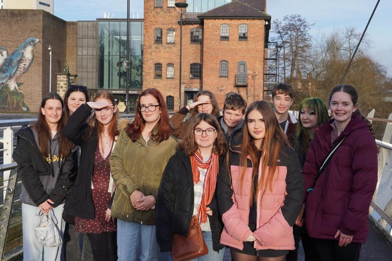 A group of young people stand on a bridge