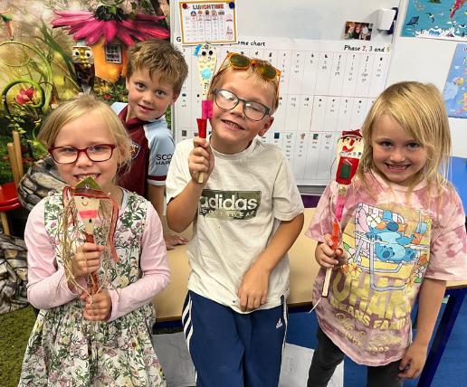 Three reception-aged children hold puppets they created during a workshop. Three reception-aged children hold puppets they created during a workshop.